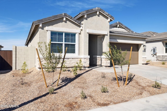 view of front of property featuring stucco siding, driveway, stone siding, a garage, and a tiled roof