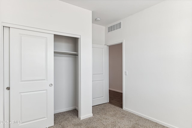 unfurnished bedroom featuring a closet, visible vents, light colored carpet, and baseboards