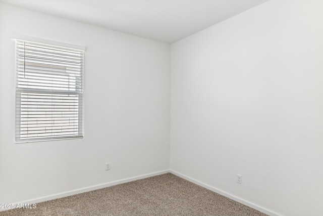 carpeted empty room featuring baseboards