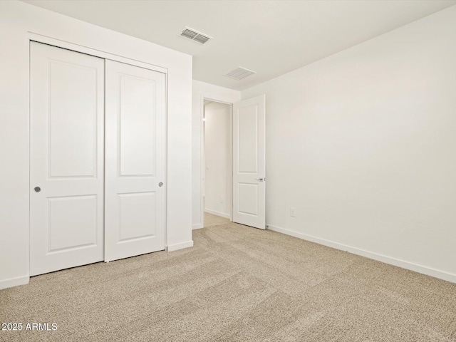 unfurnished bedroom with light colored carpet and a closet