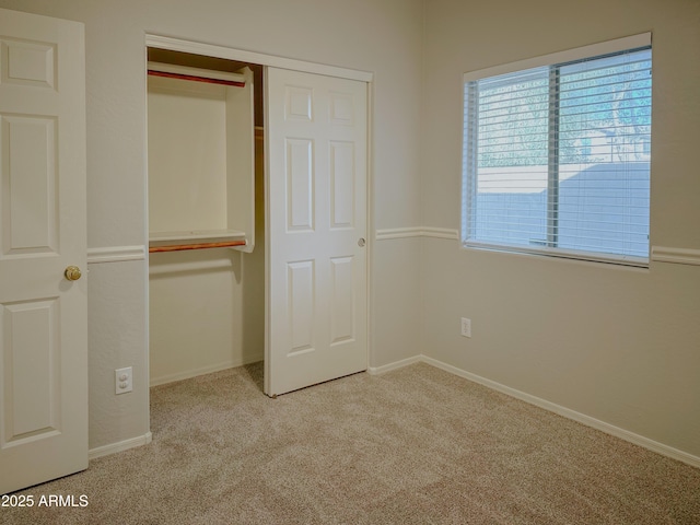 unfurnished bedroom featuring light colored carpet, multiple windows, and a closet