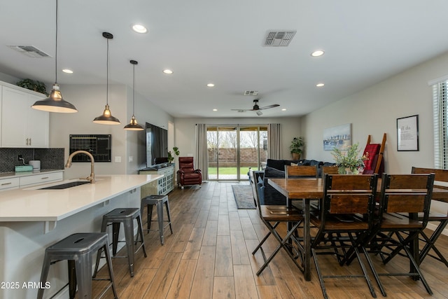 dining space with sink, ceiling fan, and light wood-type flooring