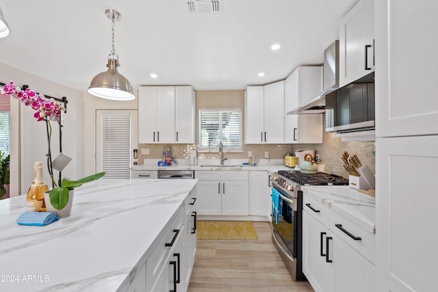 kitchen featuring white cabinetry, sink, decorative light fixtures, and appliances with stainless steel finishes