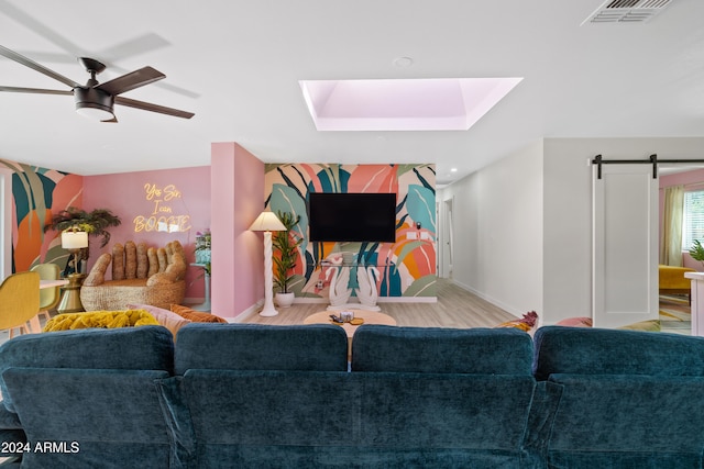 living room featuring a barn door, ceiling fan, and light hardwood / wood-style flooring