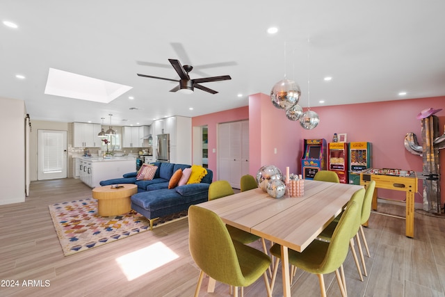 dining space featuring ceiling fan, light hardwood / wood-style floors, and a skylight