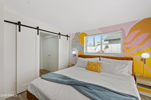 bedroom featuring hardwood / wood-style flooring, a barn door, and a closet