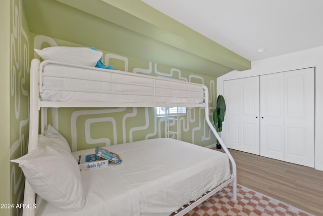 bedroom with hardwood / wood-style flooring, a closet, and lofted ceiling with beams