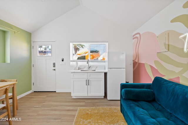 interior space with lofted ceiling, sink, and light hardwood / wood-style flooring