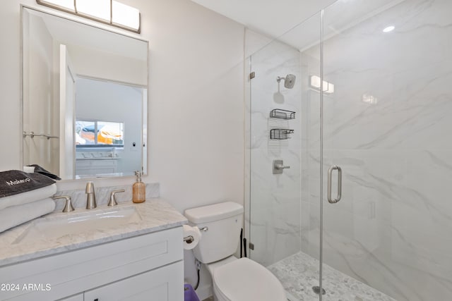 bathroom with a shower with door, vanity, and toilet