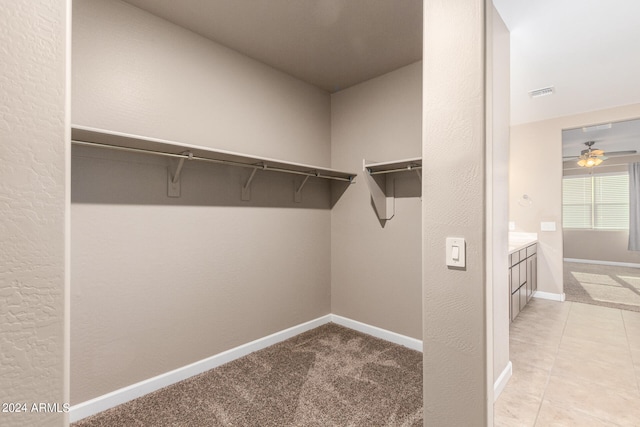 spacious closet featuring ceiling fan and light carpet