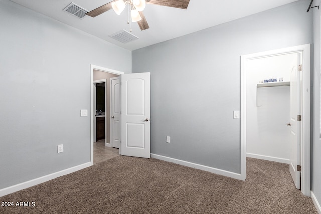 unfurnished bedroom featuring a walk in closet, ceiling fan, carpet, and a closet