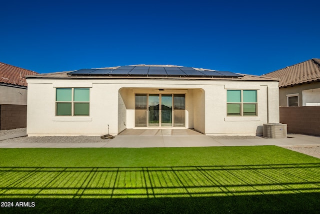 rear view of property with a yard, a patio, and solar panels