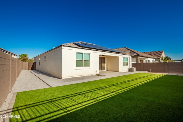 back of property with a yard, solar panels, and a patio