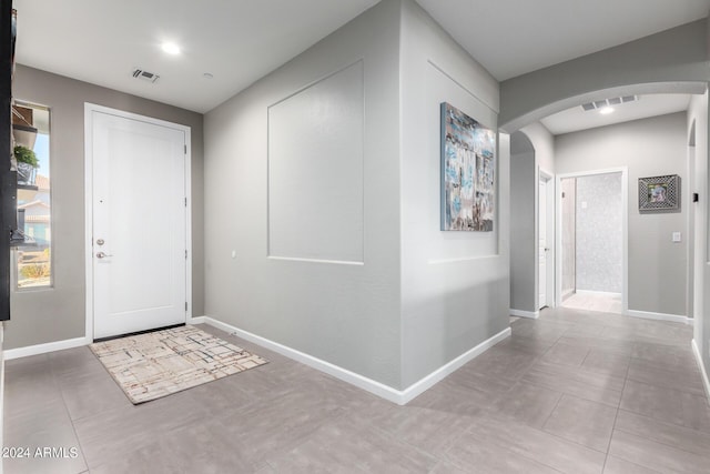 tiled foyer featuring arched walkways and baseboards
