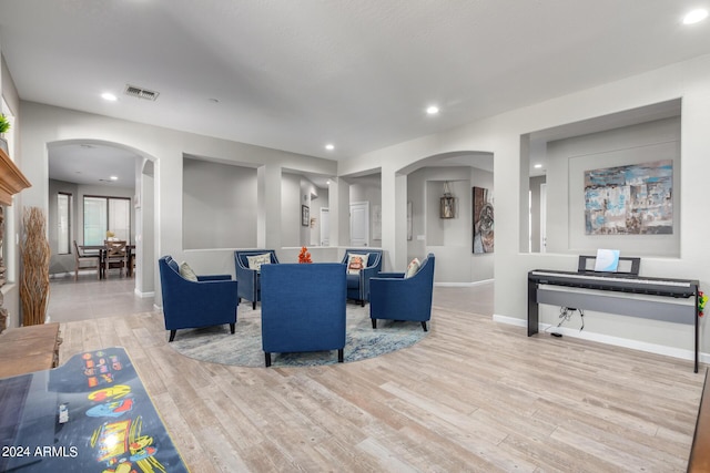 living area with arched walkways, wood finished floors, baseboards, and recessed lighting
