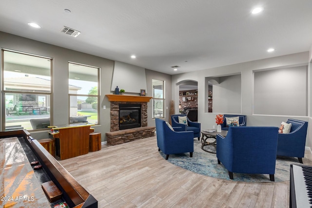 living area with wood finished floors, a stone fireplace, and recessed lighting