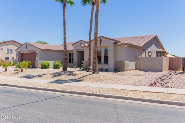 view of front of home featuring stucco siding, an attached garage, a tiled roof, and fence