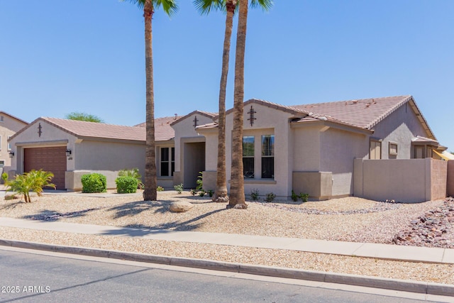 view of front facade featuring a garage, stucco siding, a tiled roof, and fence