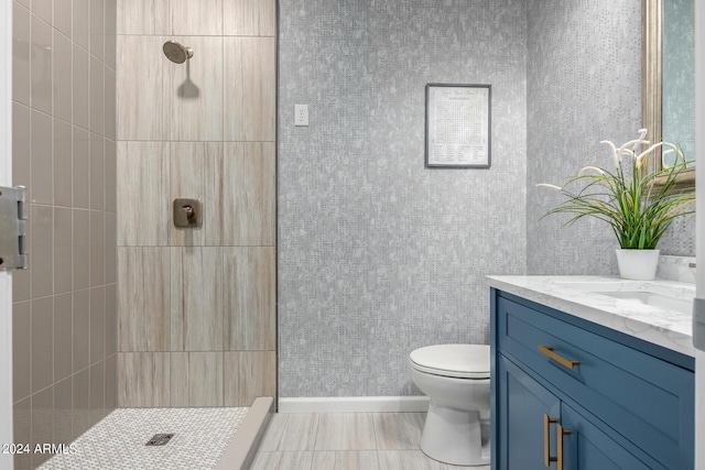 bathroom featuring tiled shower, vanity, and toilet