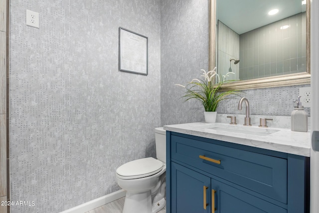 full bathroom with toilet, vanity, and a tile shower