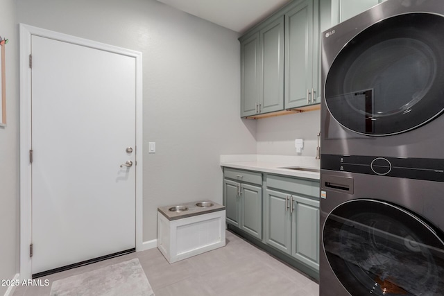 clothes washing area featuring stacked washer / dryer, cabinet space, and baseboards
