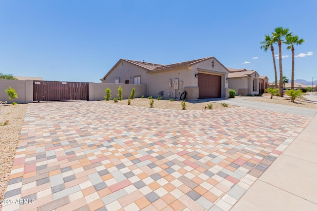 ranch-style house with decorative driveway, a gate, an attached garage, fence, and stucco siding
