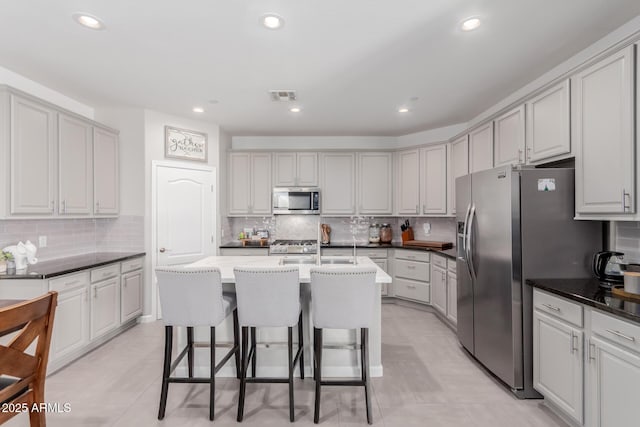 kitchen featuring appliances with stainless steel finishes, decorative backsplash, a breakfast bar, light tile patterned floors, and recessed lighting