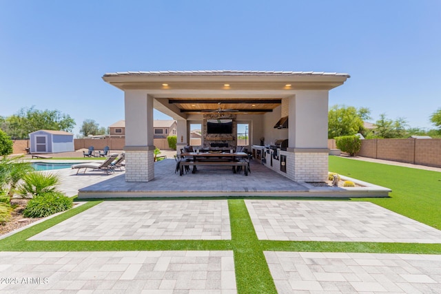 view of patio with a fenced backyard, a shed, exterior fireplace, an outdoor structure, and area for grilling