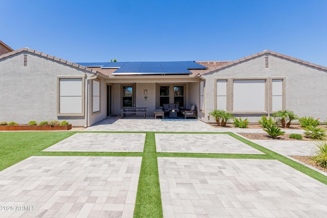 view of front of house featuring stucco siding, roof mounted solar panels, and a tile roof