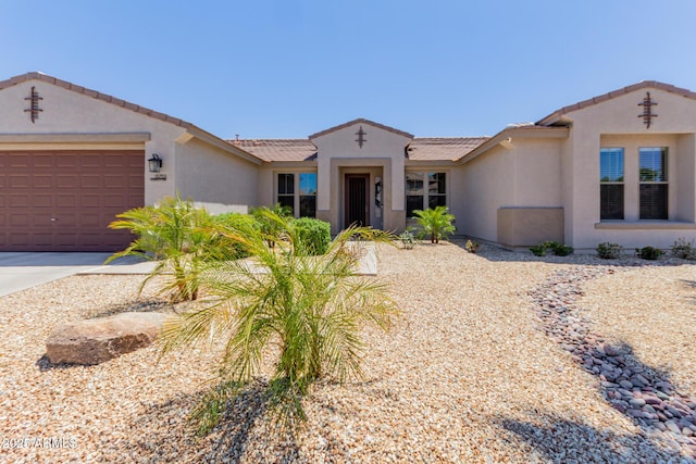 view of front of home with stucco siding, an attached garage, a tile roof, and concrete driveway