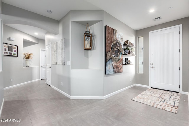 foyer entrance with arched walkways, baseboards, recessed lighting, and tile patterned floors