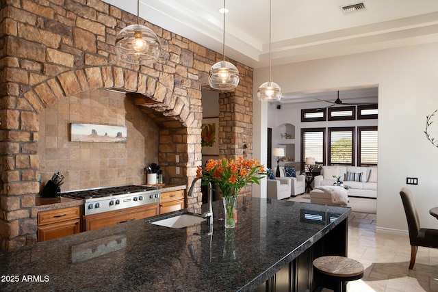 kitchen with stainless steel gas cooktop, a sink, visible vents, a kitchen breakfast bar, and hanging light fixtures