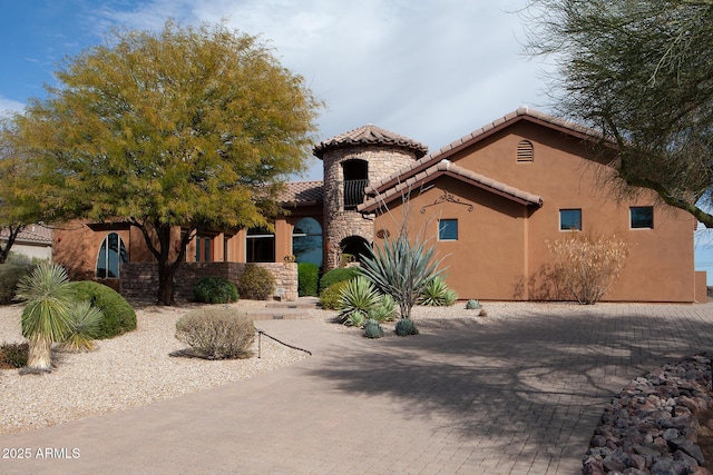 mediterranean / spanish-style home with stone siding, a tiled roof, and stucco siding