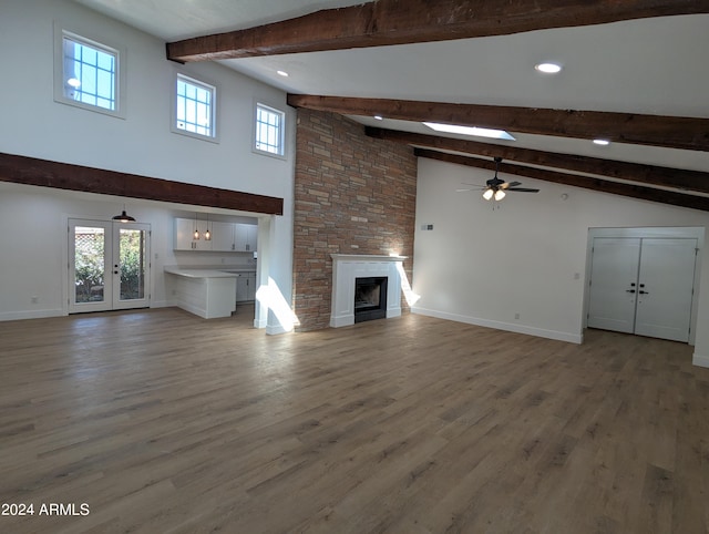 unfurnished living room featuring ceiling fan, dark wood-type flooring, high vaulted ceiling, beam ceiling, and a stone fireplace