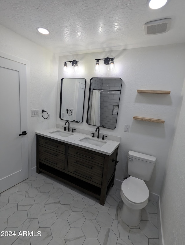 bathroom with tile flooring, double sink, a textured ceiling, toilet, and vanity with extensive cabinet space