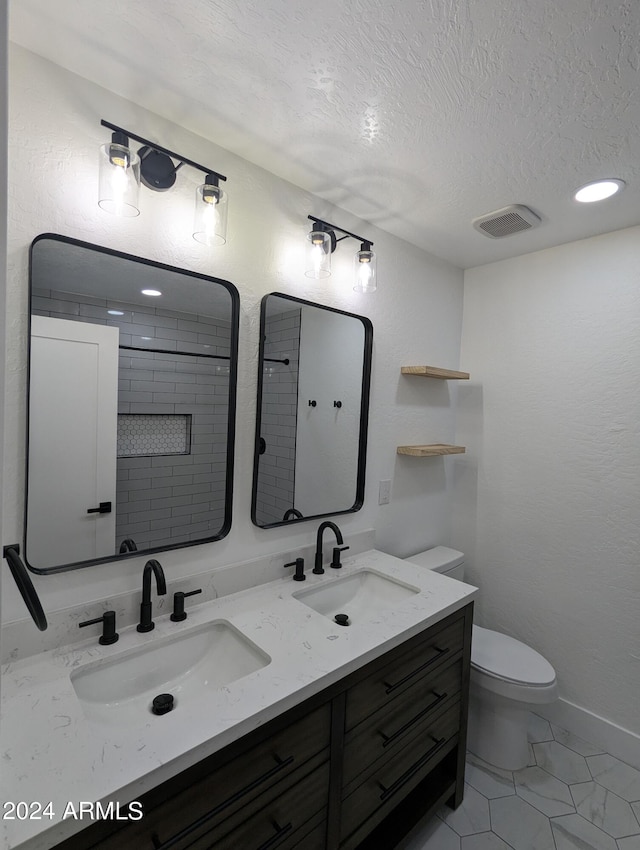 bathroom featuring toilet, double vanity, tile flooring, and a textured ceiling