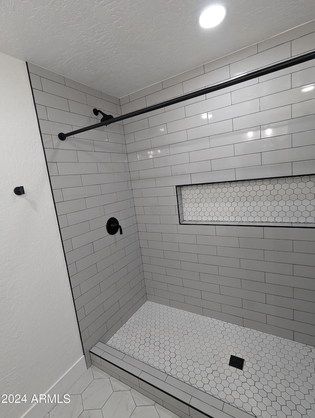 bathroom with a textured ceiling and tiled shower