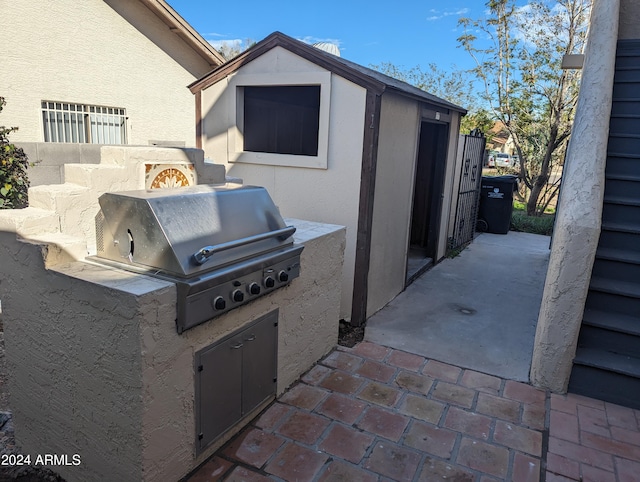 view of patio with exterior kitchen, an outdoor structure, and a grill