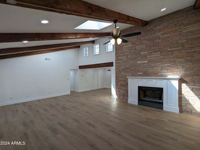 unfurnished living room with vaulted ceiling with skylight, ceiling fan, and dark hardwood / wood-style floors