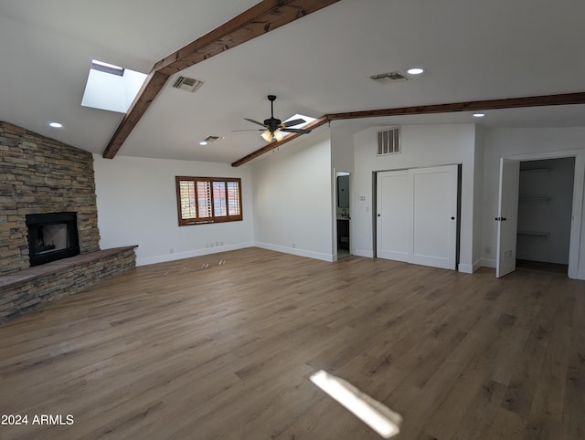 unfurnished living room with vaulted ceiling with skylight, a fireplace, ceiling fan, and light wood-type flooring