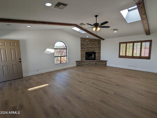 unfurnished living room featuring ceiling fan, a stone fireplace, dark wood-type flooring, and a healthy amount of sunlight