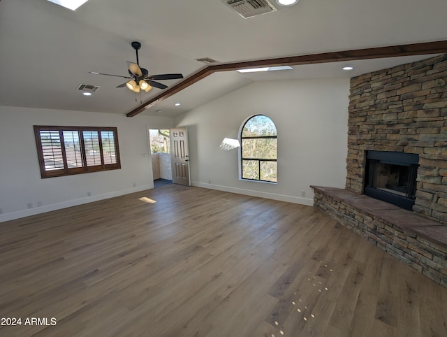 unfurnished living room with ceiling fan, dark hardwood / wood-style floors, a healthy amount of sunlight, and a stone fireplace