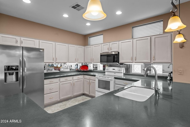 kitchen featuring a healthy amount of sunlight, appliances with stainless steel finishes, sink, and decorative light fixtures