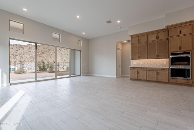 unfurnished living room featuring a mountain view and light tile patterned flooring