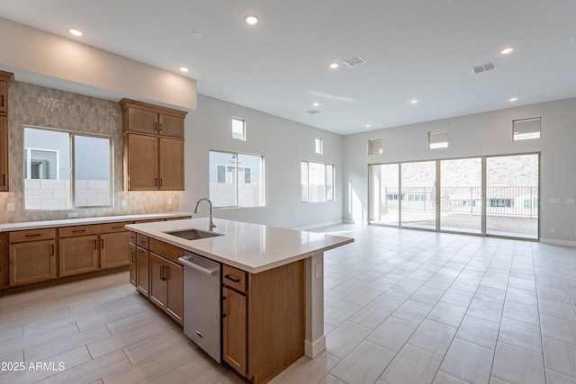 kitchen with dishwasher, a center island with sink, tasteful backsplash, and sink