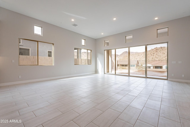 unfurnished room featuring a mountain view and a towering ceiling