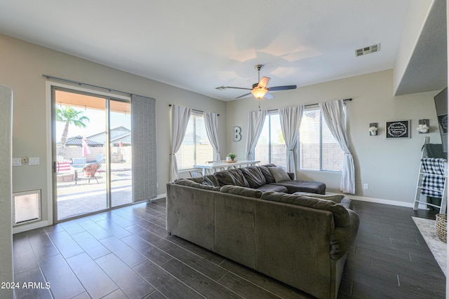 living room with baseboards, dark wood finished floors, visible vents, and a ceiling fan