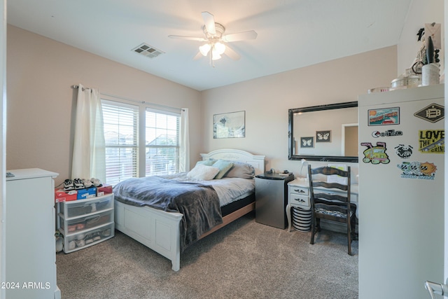 bedroom with light carpet, freestanding refrigerator, ceiling fan, and visible vents