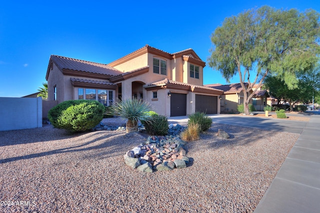 mediterranean / spanish house with a tile roof, stucco siding, concrete driveway, fence, and a garage