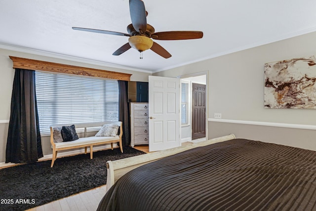 bedroom featuring a ceiling fan, baseboards, crown molding, and wood finished floors